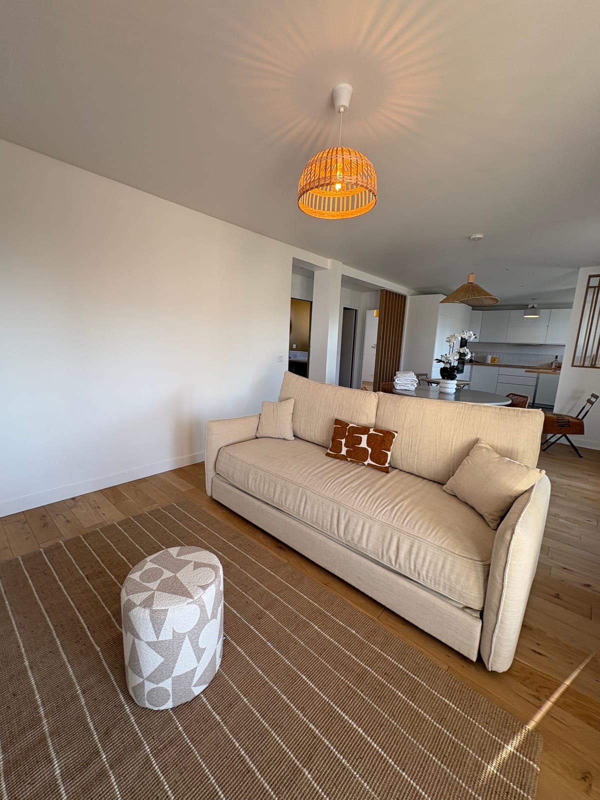 Canapé en lin et tapis de jute, sous une suspension en rotin tressé — Sanary-sur-Mer — deux appartements meublés